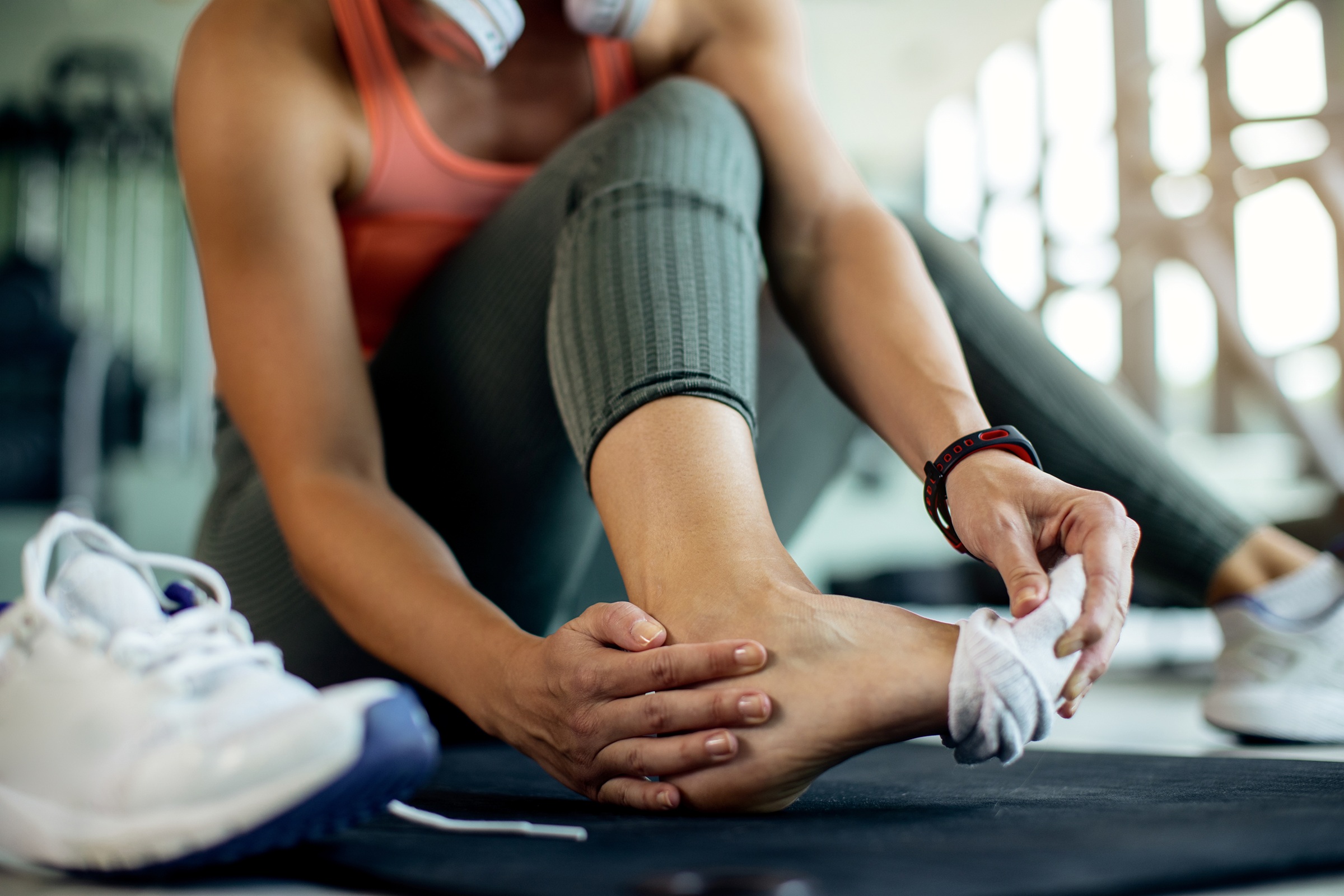 Close-up of female athlete holding her ankle in pain